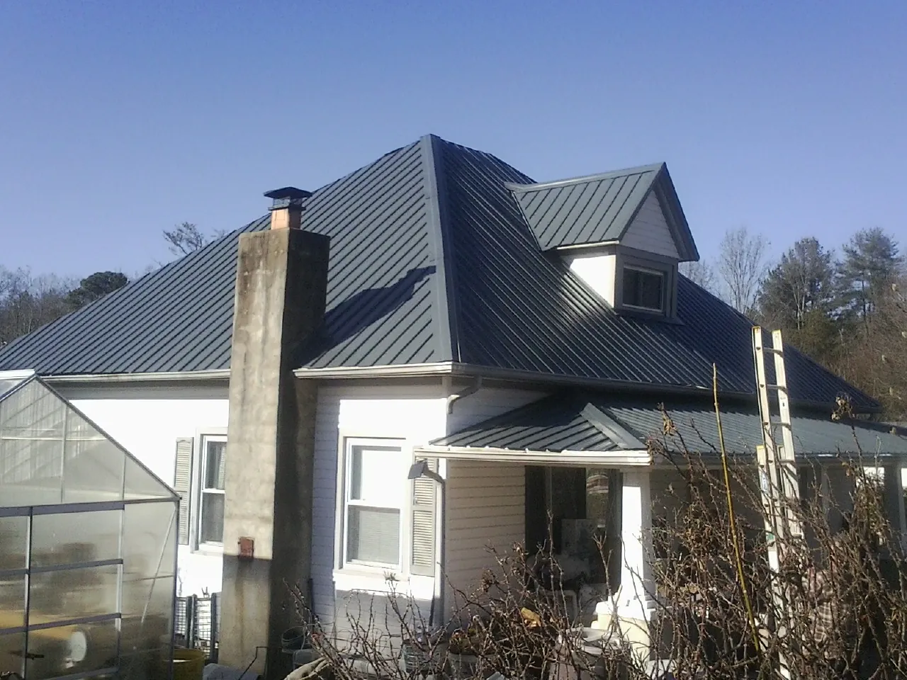Dark blue standing seam metal roof on a white farmhouse with dormer — Slate & Tile Roof Repair by Roofing Brothers in Barhamsville