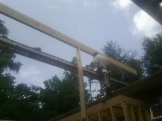 Carpenter setting a ridge beam over a new addition frame — Ice Dam Removal by Roofing Brothers in Barhamsville