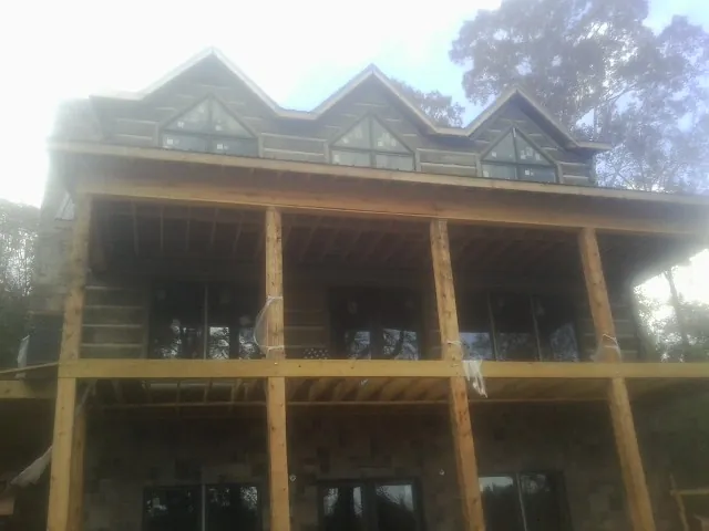 Dormers and porch framing on a large log home under construction — Roof Coating work by our crew in Barhamsville