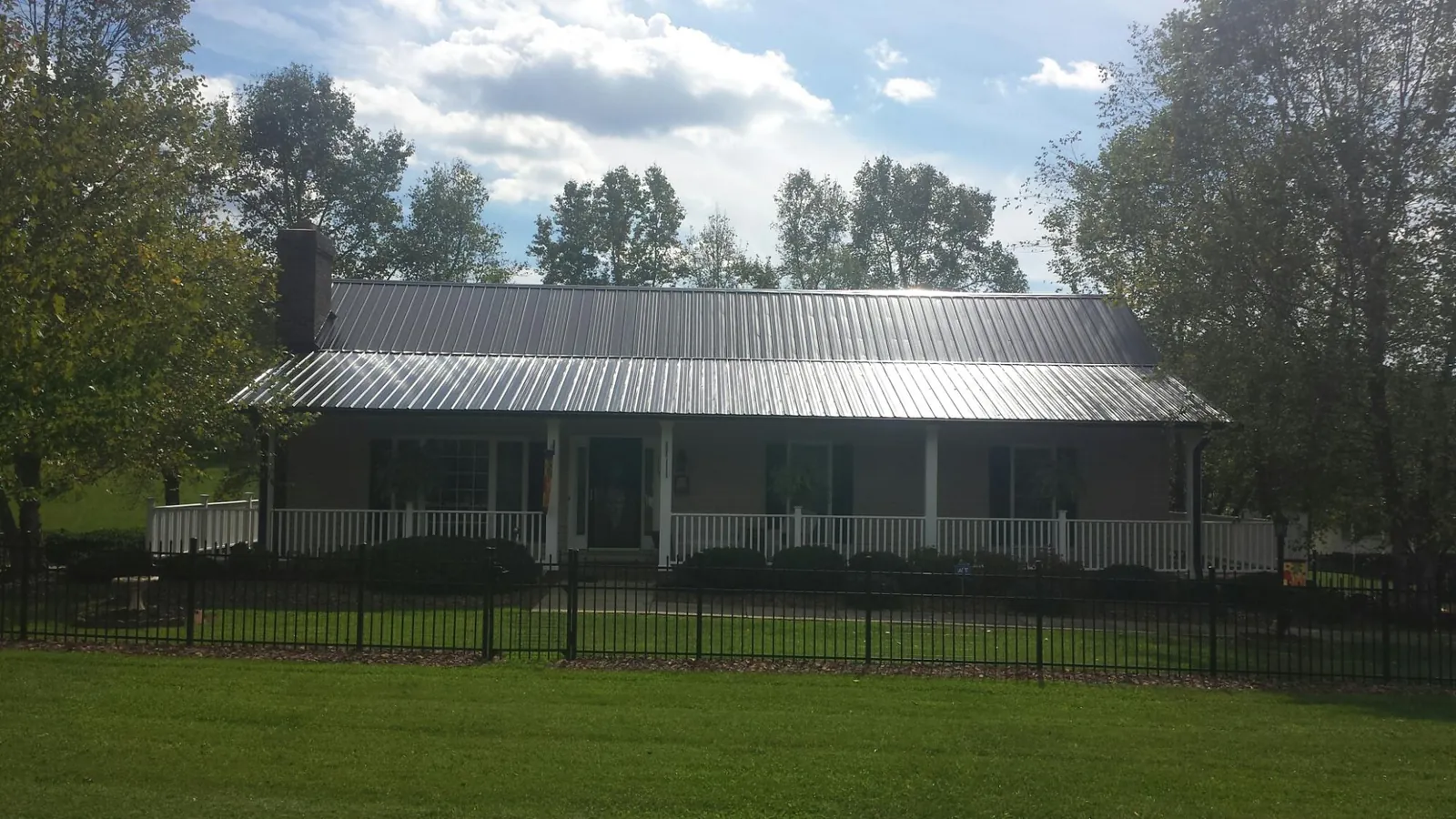 Gray metal roof on a brick ranch with a full width front porch — Gutter Guard Installation work by our crew in Barhamsville