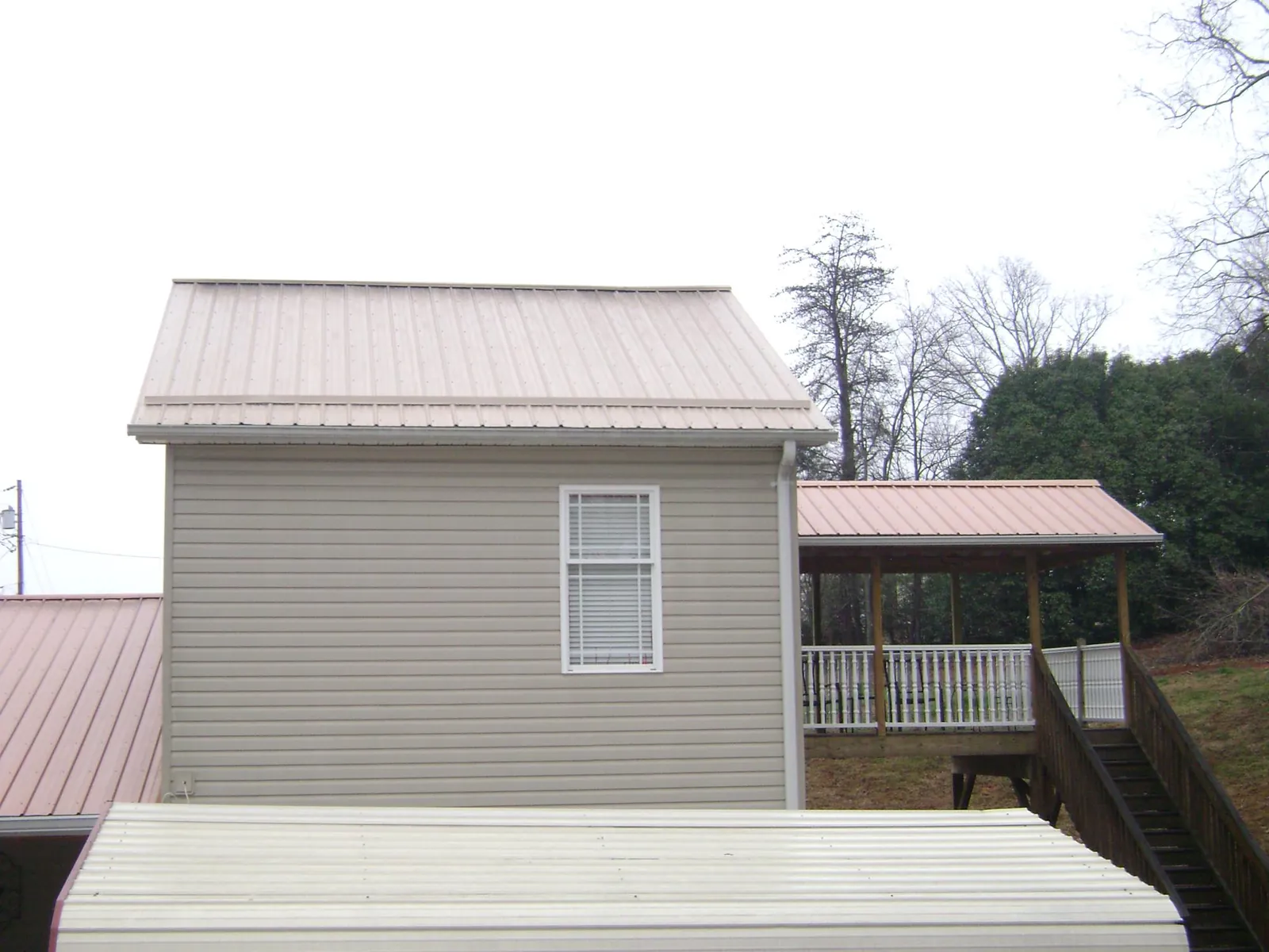 Tan metal roofs on a two story addition and attached porch, from a Roof Replacement job in Barhamsville