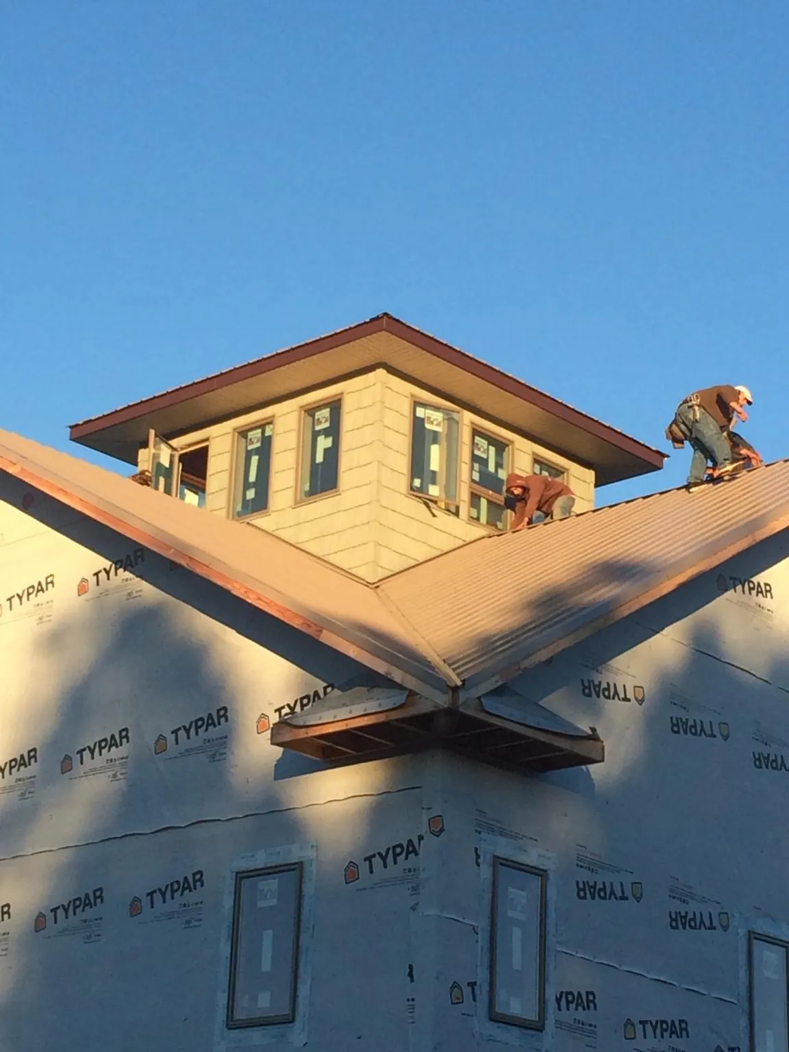 Roofers working around a rooftop cupola on a new metal roof at sunset — Roof Waterproofing in Barhamsville by Roofing Brothers